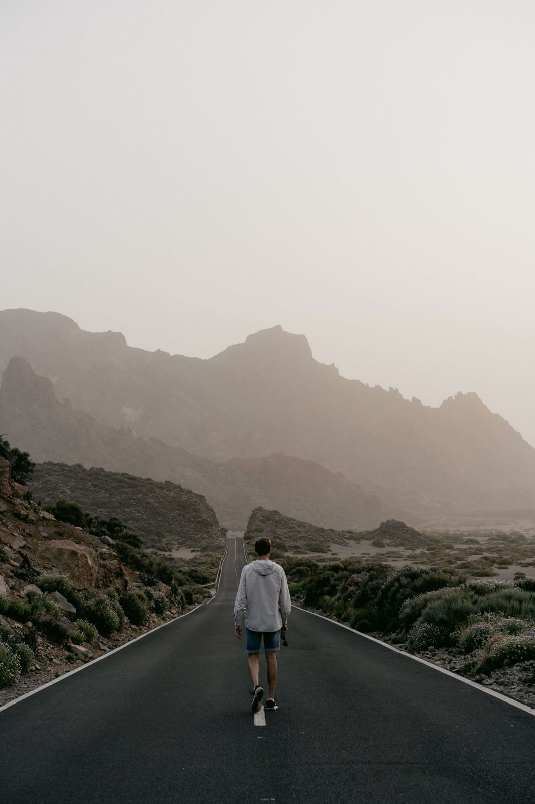 A man walking alone along a misty mountain road